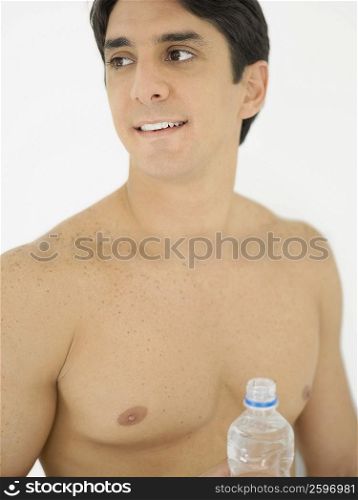 Close-up of a mid adult man holding a water bottle and looking sideways