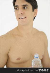 Close-up of a mid adult man holding a water bottle and looking sideways