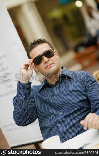 Close-up of a mid adult man holding his sunglasses