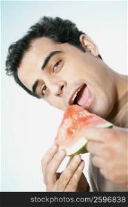 Close-up of a mid adult man holding watermelon slice with his mouth open
