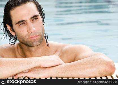 Close-up of a mid adult man leaning at the edge of a swimming pool