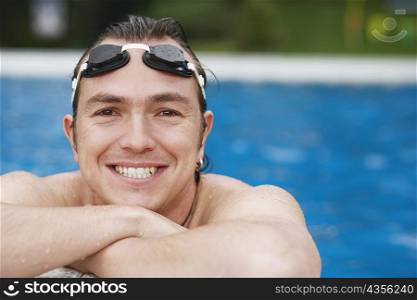 Close-up of a mid adult man leaning at the edge of a swimming pool