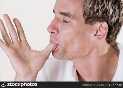 Close-up of a mid adult man licking his thumb