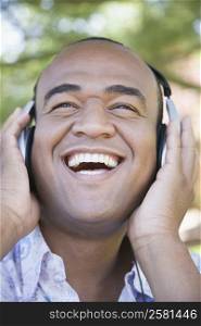 Close-up of a mid adult man listening to music with headphones and laughing