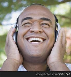 Close-up of a mid adult man listening to music with headphones and smiling