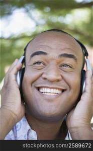 Close-up of a mid adult man listening to music with headphones and smiling