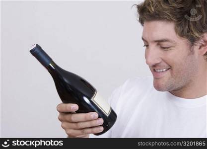 Close-up of a mid adult man looking at a champagne bottle and smiling