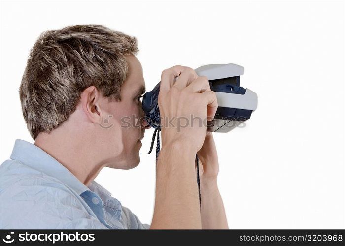 Close-up of a mid adult man looking through an instant camera