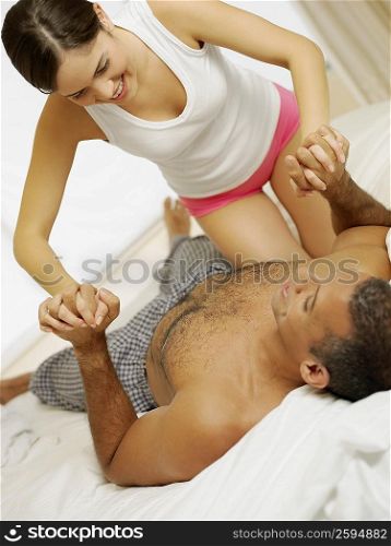 Close-up of a mid adult man lying on the bed and young woman bending forward