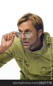 Close-up of a mid adult man peeking over his sunglasses