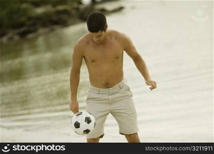 Close-up of a mid adult man playing with a soccer ball on the beach