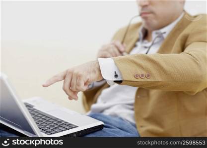 Close-up of a mid adult man pointing at a laptop