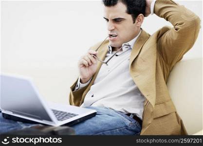 Close-up of a mid adult man sitting with a laptop and thinking