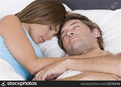 Close-up of a mid adult man sleeping on the bed with a young woman