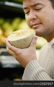 Close-up of a mid adult man smelling the cross section of a cantaloupe