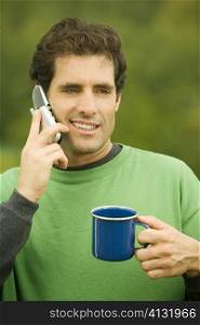 Close-up of a mid adult man talking on a mobile phone holding a coffee cup