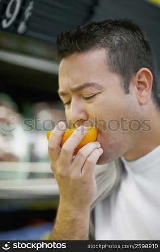 Close-up of a mid adult man tasting an orange