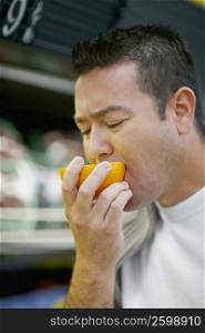 Close-up of a mid adult man tasting an orange