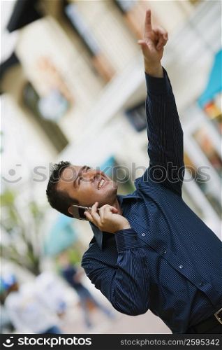 Close-up of a mid adult man using a mobile phone and pointing up