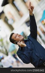 Close-up of a mid adult man using a mobile phone and pointing up