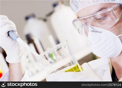 Close-up of a mid adult man using a pipette in a beaker