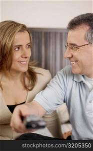 Close-up of a mid adult man using a remote control beside a mid adult woman