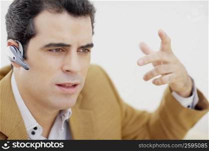 Close-up of a mid adult man wearing a hands free device and gesturing