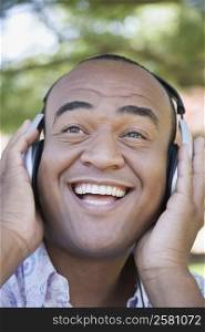 Close-up of a mid adult man wearing headphones and listening to music and smiling