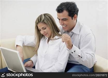 Close-up of a mid adult man with a mid adult woman using a laptop