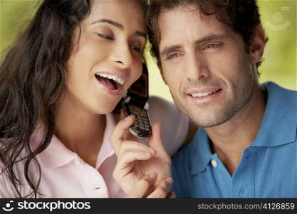 Close-up of a mid adult man with a young woman holding a mobile phone