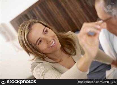 Close-up of a mid adult woman adjusting the eyeglasses of a mid adult man