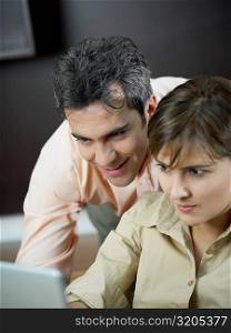 Close-up of a mid adult woman and a mature man using a laptop