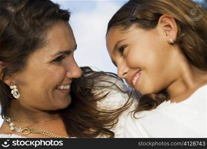 Close-up of a mid adult woman and her daughter looking at each other and smiling