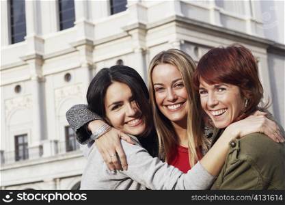 Close-up of a mid adult woman and two young women hugging