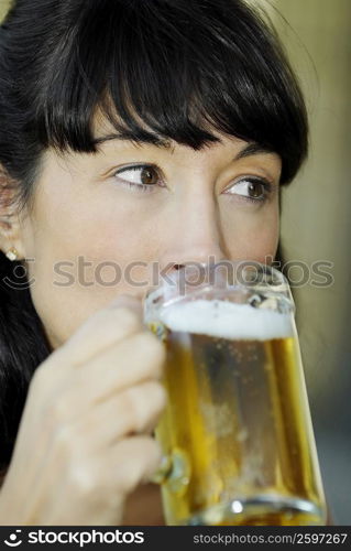 Close-up of a mid adult woman drinking a glass of beer