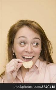 Close-up of a mid adult woman eating a potato chip and smiling