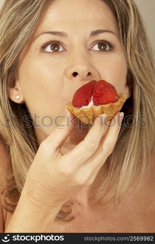 Close-up of a mid adult woman eating a strawberry tart