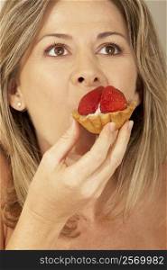 Close-up of a mid adult woman eating a strawberry tart