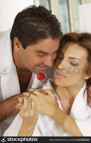 Close-up of a mid adult woman feeding a mid adult man a strawberry