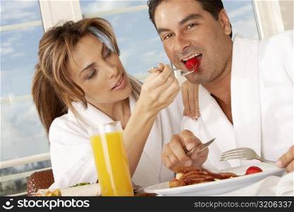 Close-up of a mid adult woman feeding a strawberry to a mid adult man