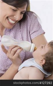 Close-up of a mid adult woman feeding her son with a baby bottle