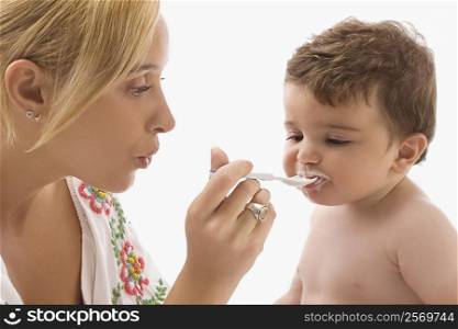 Close-up of a mid adult woman feeding her son with a spoon