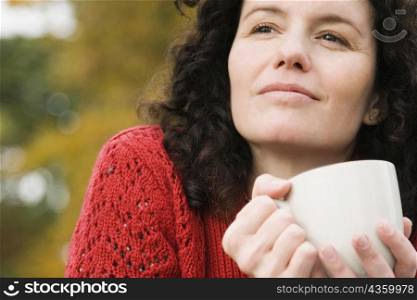 Close-up of a mid adult woman holding a coffee cup and thinking