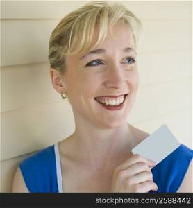 Close-up of a mid adult woman holding a credit card and smiling