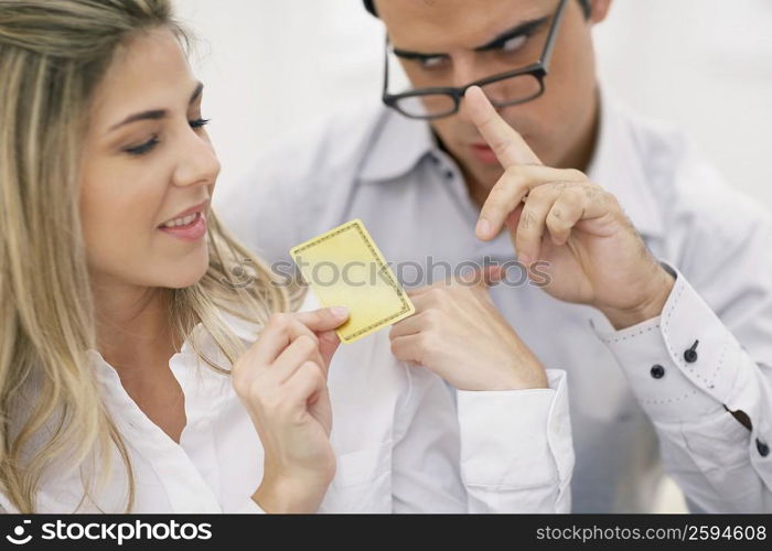 Close-up of a mid adult woman holding a credit card with a mid adult man looking at her