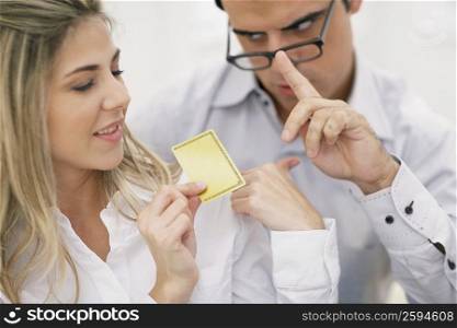 Close-up of a mid adult woman holding a credit card with a mid adult man looking at her