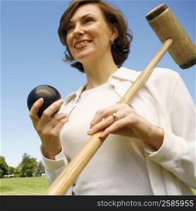 Close-up of a mid adult woman holding a croquet mallet and a ball