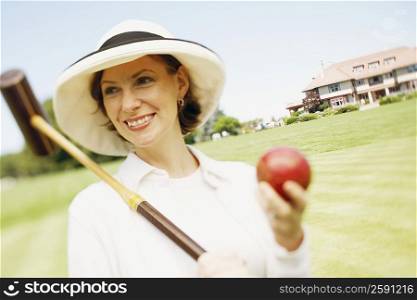 Close-up of a mid adult woman holding a croquet mallet and a ball