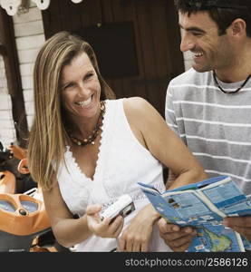 Close-up of a mid adult woman holding a digital camera and a mid adult man holding a catalog and smiling