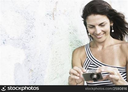 Close-up of a mid adult woman holding a digital camera and smiling